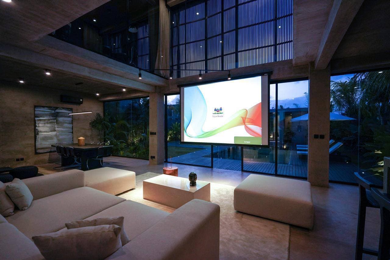 Villa living room with projector screen and concrete interior at night — Frigate Bali